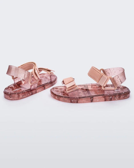 Angled view of a pair of Melissa Wide Papete sandal with transparent pink glitter sole with pink velcro straps 