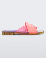 Side view of a pink/green/lilac Melissa Brigitte slide with a pink weft designed upper strap and purple and green insole.