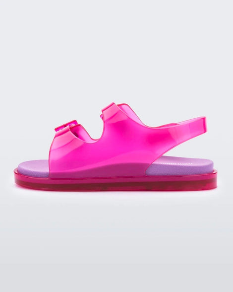 An inner side view of a pink/lilac Mini Melissa Wide Sandal with a pink base, two pink buckles on top, a back ankle strap and a lilac insole.