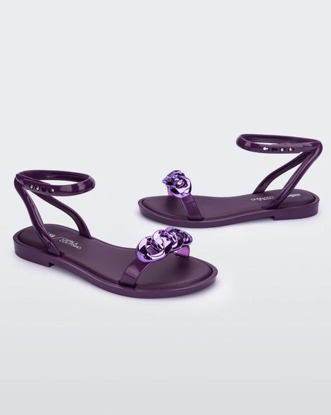 Side view of a pair of purple Melissa Dare sandals with a purple metal chain buckle.