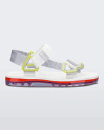 Side view of a pair of white Melissa Papete sandals with white and clear straps with yellow buckles.