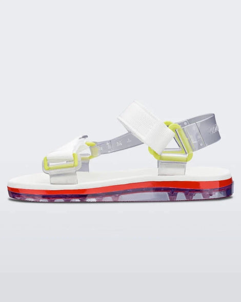 Side view of a pair of white Melissa Papete sandals with white and clear straps with yellow buckles.