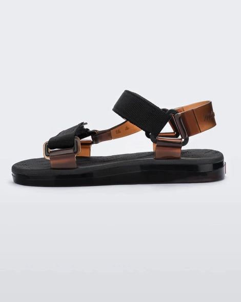 Side view of a pair of black Melissa Papete sandals with black and transparent brown straps.