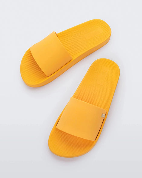 Top view of a pair of yellow Melissa Sun Sunset slides with a melissa logo on the side.