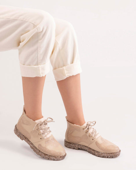 A model's legs wearing a pair of Beige Flecked/Glitter Melissa Fluffy Boots with laces and a rubber sole.