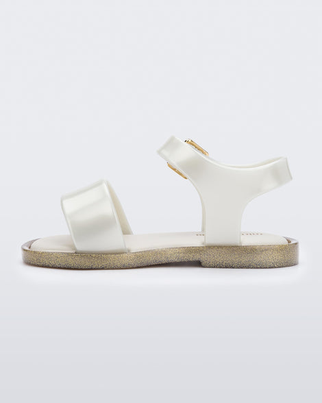 An inner side view of a white Mini Melissa Mar Sandal with two straps and a gold buckle.