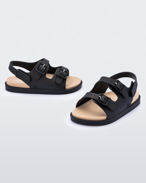 An angled front and side view of a pair of black/beige Mini Melissa Wide Sandals with a black base, two black buckles at the top and a beige insole.