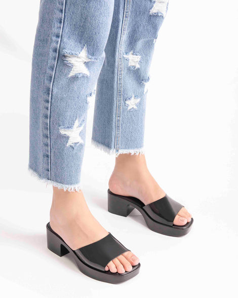A model's legs wearing a pair of Melissa Shape slides in black 