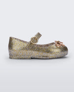 Side view of a Gold/Silver/Glitter Mini Melissa Sweet Love flat with a top strap and a bow detail on the toe.